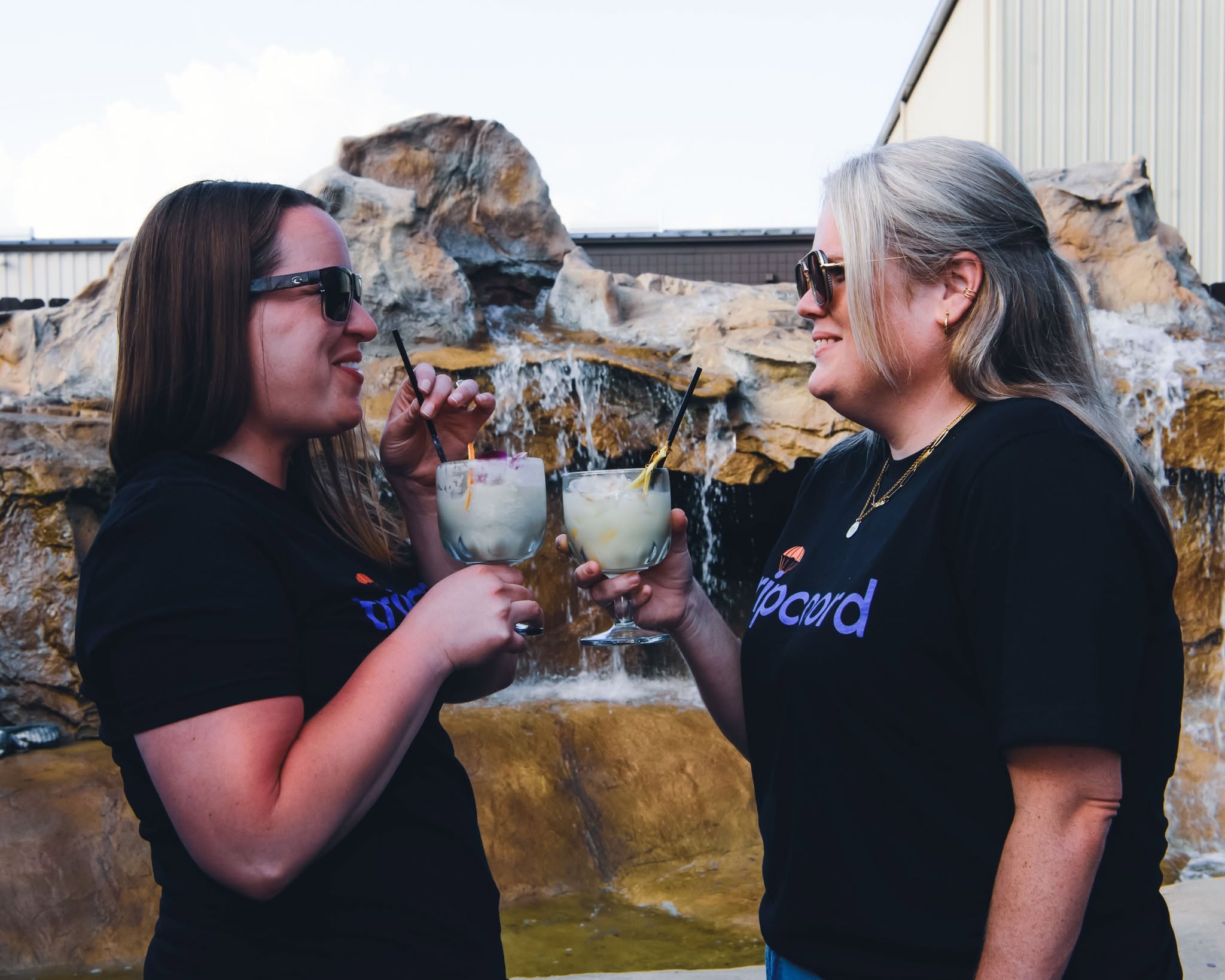 Two friends toasting drinks outdoors